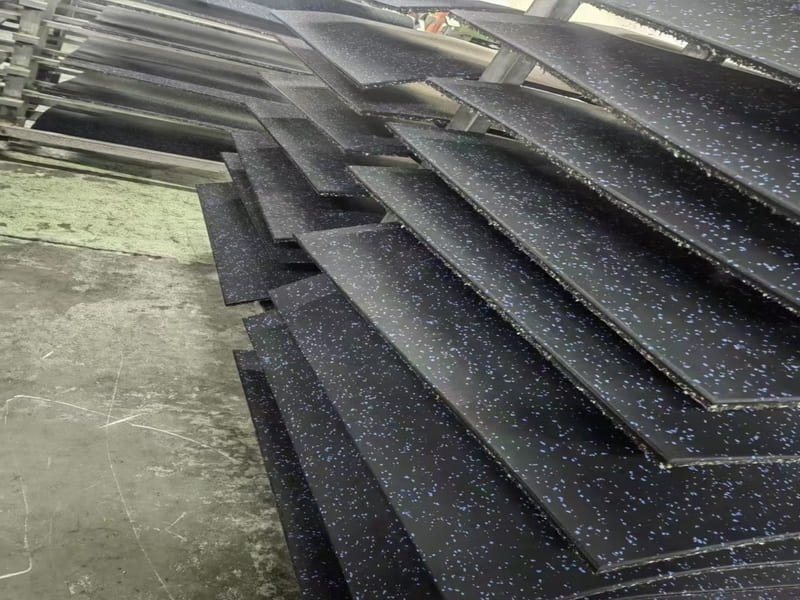 An acoustic underlayment being installed underneath rubber gym tiles in a multi-story building